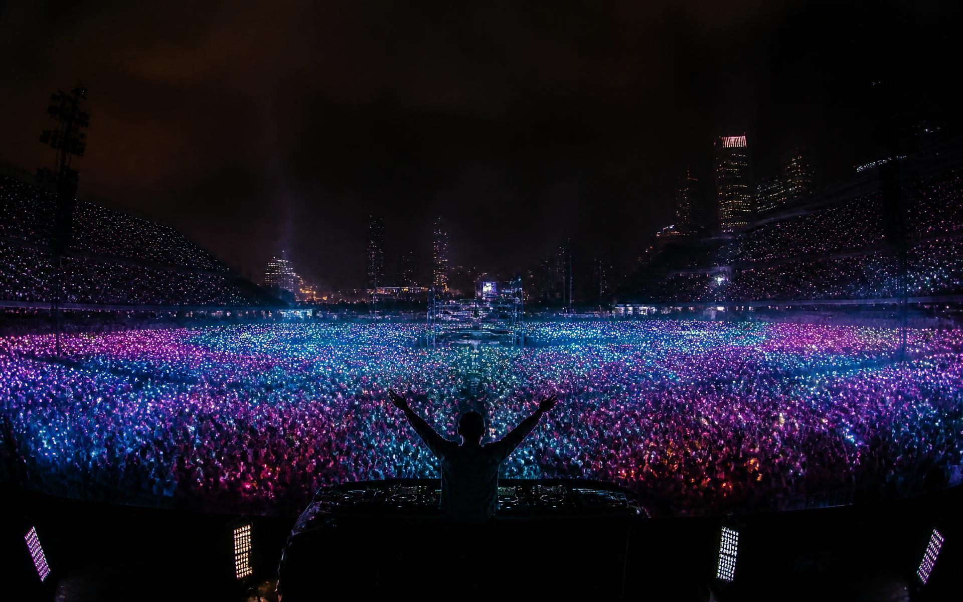 A stadium crowd holding up thousands of phones glowing in synchronised colour